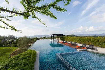 an infinity pool with chairs and a view of a vineyard at 6th Avenue Surin Condomium in Surin Beach