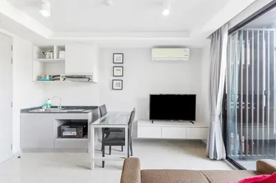 a white living room with a table and a television at 6th Avenue Surin Condomium in Surin Beach