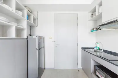 a white kitchen with a refrigerator and a sink at 6th Avenue Surin Condomium in Surin Beach