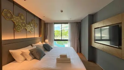 a bedroom with a large bed with a tv on the wall at Apartment 5 Star Hotel LaVita in Rawai Beach