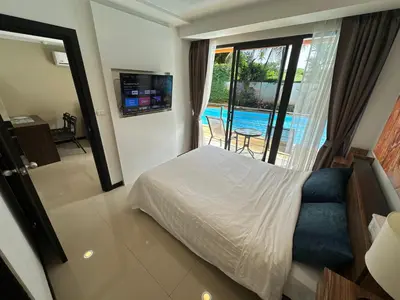 a bedroom with a bed and a view of a pool at 1 - Bedroom Apartment Pool Access, 750m to the Beach in Mai Khao Beach
