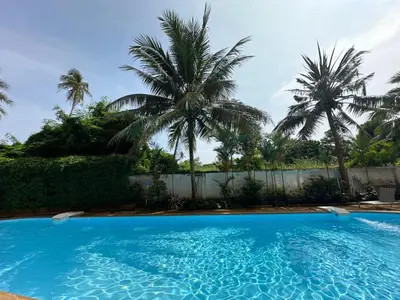 a blue swimming pool with palm trees in the background at 1 - Bedroom Apartment Pool Access, 750m to the Beach in Mai Khao Beach