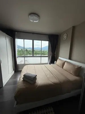 a bedroom with a large bed with a large window at D-Condo Mine Kathu in Ban Ket Ho