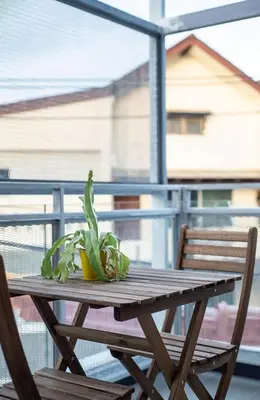 a wooden table with a potted plant on a balcony at Kata Beach Poshtel Phuket in Kata Beach