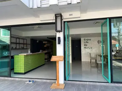 an open glass door of a building with a bench at Kata Beach Poshtel Phuket in Kata Beach