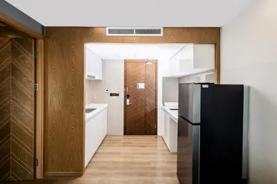 a kitchen with a black refrigerator and white cabinets at Suite Marella 1BR Pools Shuttle to Nai Harn in Rawai Beach