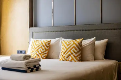 a bed with pillows and a pile of towels on it at Suite Marella 1BR Pools Shuttle to Nai Harn in Rawai Beach
