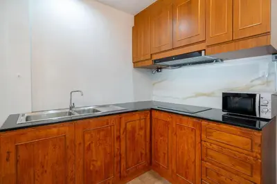 a kitchen with wooden cabinets and a sink and a microwave at Patong private home 4BR Jazzuci sleep 10 in Patong Beach