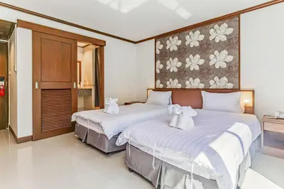 two beds in a hotel room with towels on them at Rattana Karon Beach Hotel in Karon Beach