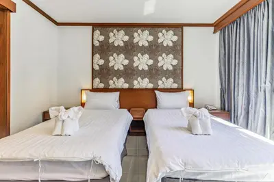 two beds in a hotel room with towels at Rattana Karon Beach Hotel in Karon Beach