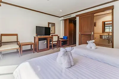 a hotel room with two towels on two beds at Rattana Karon Beach Hotel in Karon Beach