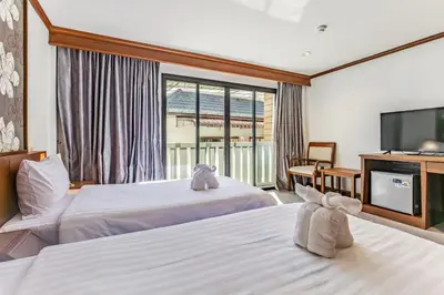 a hotel room with two beds and a flat screen tv at Rattana Karon Beach Hotel in Karon Beach