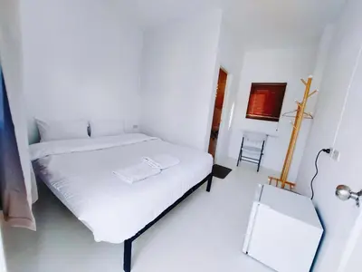 a white bedroom with a white bed and a chair at XX Bao Patong Beach PHUKET เบา หาดป่าตอง ภูเก็ต in Patong Beach