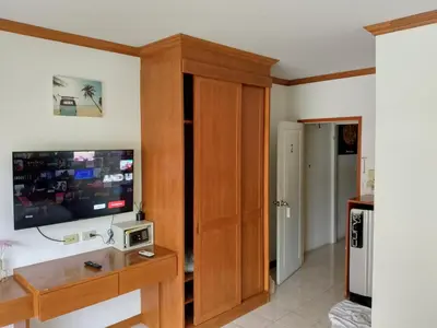 a living room with a television and a wooden cabinet at Kata Goran in Kata Beach