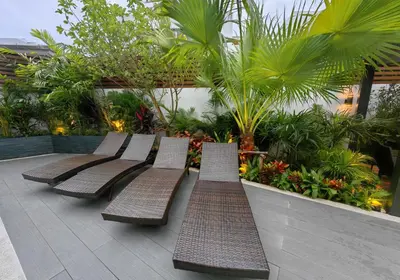 a row of benches sitting on a patio with plants at Bangtao Luxury Pool Villa - PrymaVerde in Laguna Phuket