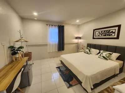 a bedroom with a bed and a table and a window at Mama's Cozy Studio - Patong Beach in Patong Beach