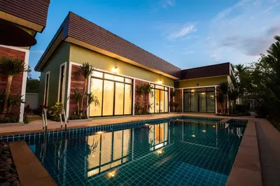 a swimming pool in front of a house at Jinda Resort in Nai Yang Beach