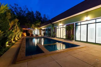 a swimming pool in front of a house at night at Jinda Resort in Nai Yang Beach