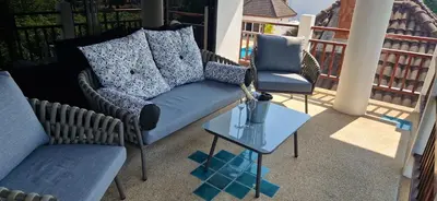 a porch with a couch and two chairs and a table at Two bedroom apartment near Naiharn beach in Nai Harn Beach