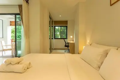 a bedroom with a large white bed with towels on it at Cozy 1BR Poolside Apartment with Scenic Balcony C132 in Surin Beach