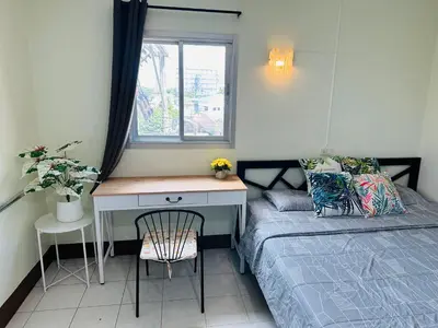 a bedroom with a bed and a desk next to a window at KLApartment in Ban Bang Chak