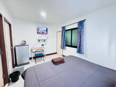 a bedroom with a bed and a window and a desk at KLApartment in Ban Bang Chak