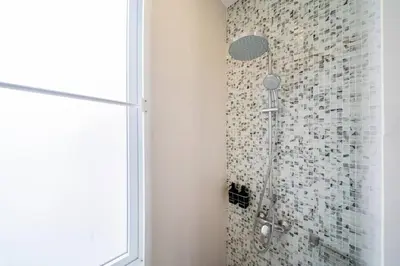 a shower in a bathroom with a tile wall at Patong WiN HOUSE Villa in Patong Beach
