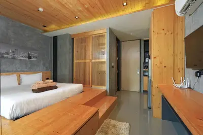 a bedroom with a large bed with a wooden bench at Relife Windy B226 at NaiHarn beach by CapitalPro in Phuket Town