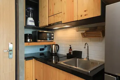 a kitchen with a stainless steel sink and wooden cabinets at Relife Windy B226 at NaiHarn beach by CapitalPro in Phuket Town