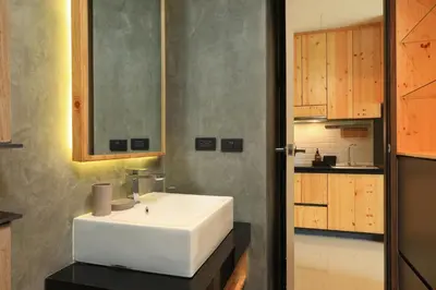 a bathroom with a white sink and wooden cabinets at Relife Windy B226 at NaiHarn beach by CapitalPro in Phuket Town