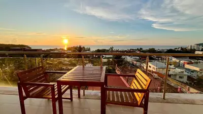 a table and two chairs on a balcony with the sunset at Sunset Plaza Condominium in Karon Beach