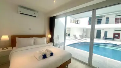 a bedroom with a bed and a swimming pool at Sunset Plaza Condominium in Karon Beach