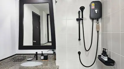 a bathroom with a shower with a sink and a mirror at Mango Moon Phuket Tropical 2BR near Central Phuket in Ban Rangeng