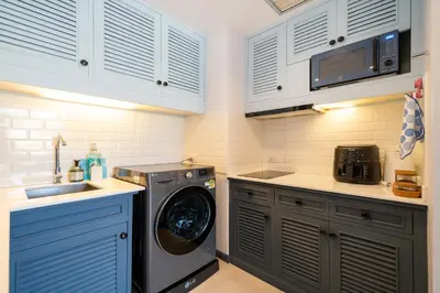 a kitchen with a washing machine and a microwave at Allamanda Laguna Phuket in Laguna Phuket