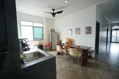 a kitchen and dining room with a table and a refrigerator at Amahostel in Ban Thalat Choeng Thale