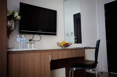 a television on a wall with a chair in a room at Royal Waves Hotel in Patong Beach