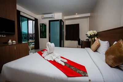 a bedroom with a large white bed with a red blanket at Royal Waves Hotel in Patong Beach