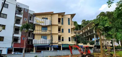 a tall yellow building with a sign on it at Royal Waves Hotel in Patong Beach