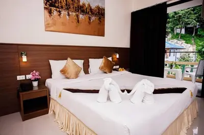 a bedroom with a large white bed with towels on it at Royal Waves Hotel in Patong Beach