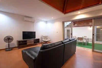 a living room with a black leather couch and a television at Balinese 3BR Pool Villa Freya, Spacious Courtyard, 70 m from Stay Wellbeing & Lifestyle in Rawai Beach