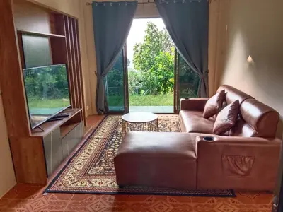 a living room with a brown couch and a television at Green House 2 in Ban Na Nai
