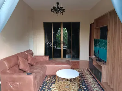 a living room with a brown leather couch and a tv at Green House 2 in Ban Na Nai