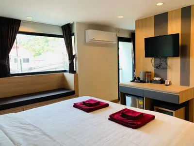 a bedroom with a bed with two red pillows on it at Room Actually in Karon Beach