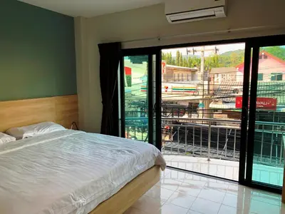a bedroom with a bed and a large glass window at Room Actually in Karon Beach