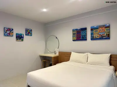 a bedroom with a bed and a desk with a mirror at Siri Hotel Phuket in Phuket Town