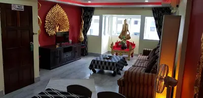 a living room with red walls and a table and chairs at Fong Kaew and Baan Nang Fa Guesthouse in Patong Beach