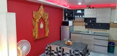 a kitchen with a red wall with a table and a mirror at Fong Kaew and Baan Nang Fa Guesthouse in Patong Beach