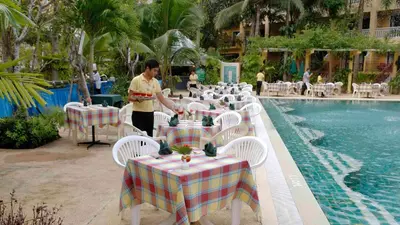 a man standing in front of a row of tables next to a pool at Successive BeachFront ,Krabi in Ban Khlong Haeng