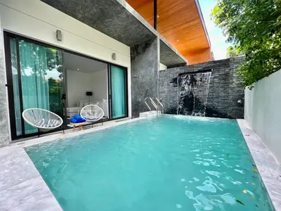 an indoor swimming pool with two chairs and a swimming house at 2 BR Modern Pool Villa Chalong in Ban Suan