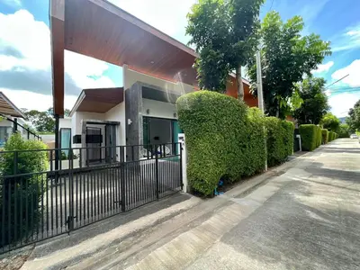 a house with a fence and hedges in front of it at 2 BR Modern Pool Villa Chalong in Ban Suan